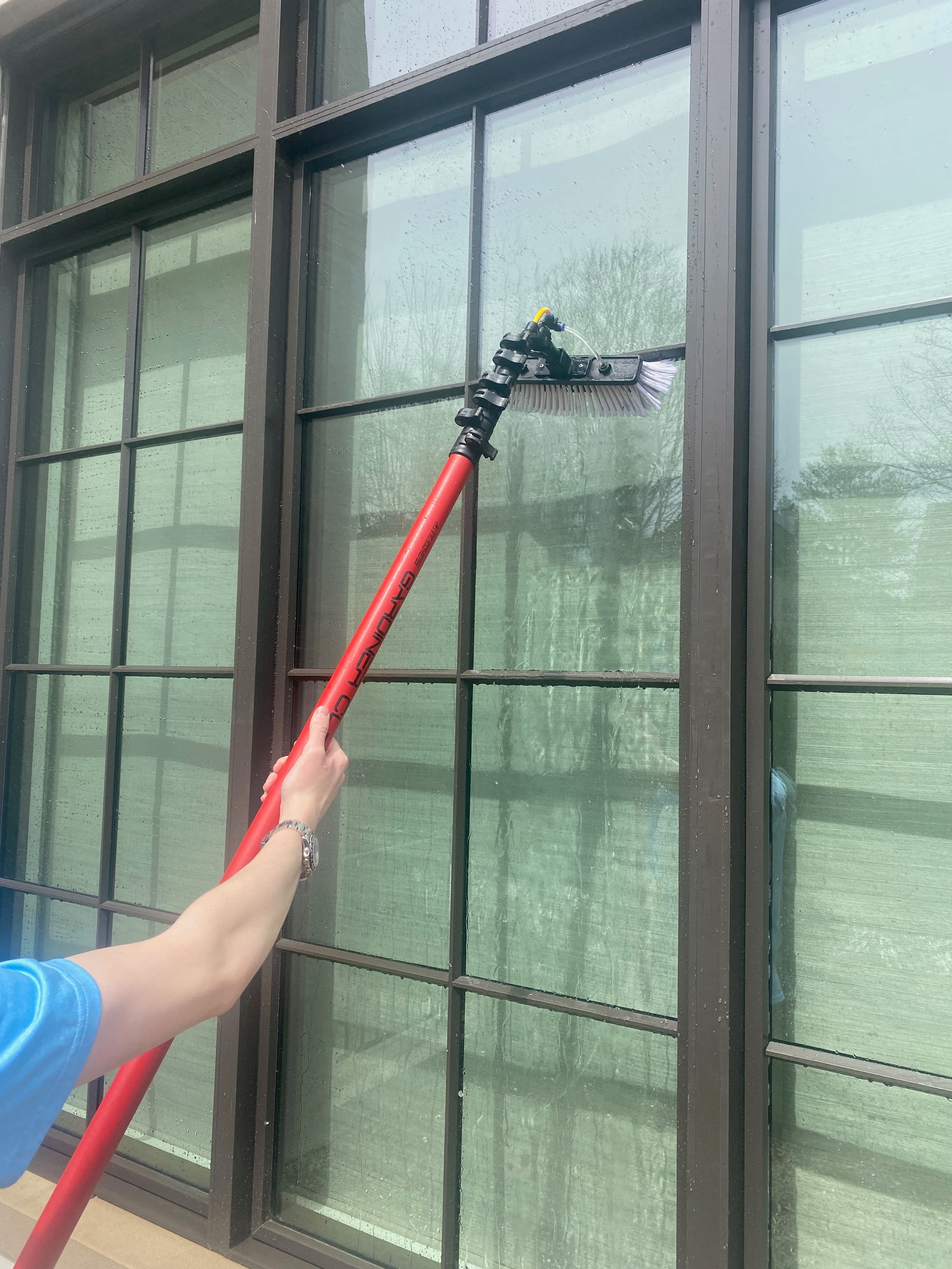 Super Shine Services technician using an extension pole brush to clean a glass skylight roof structure