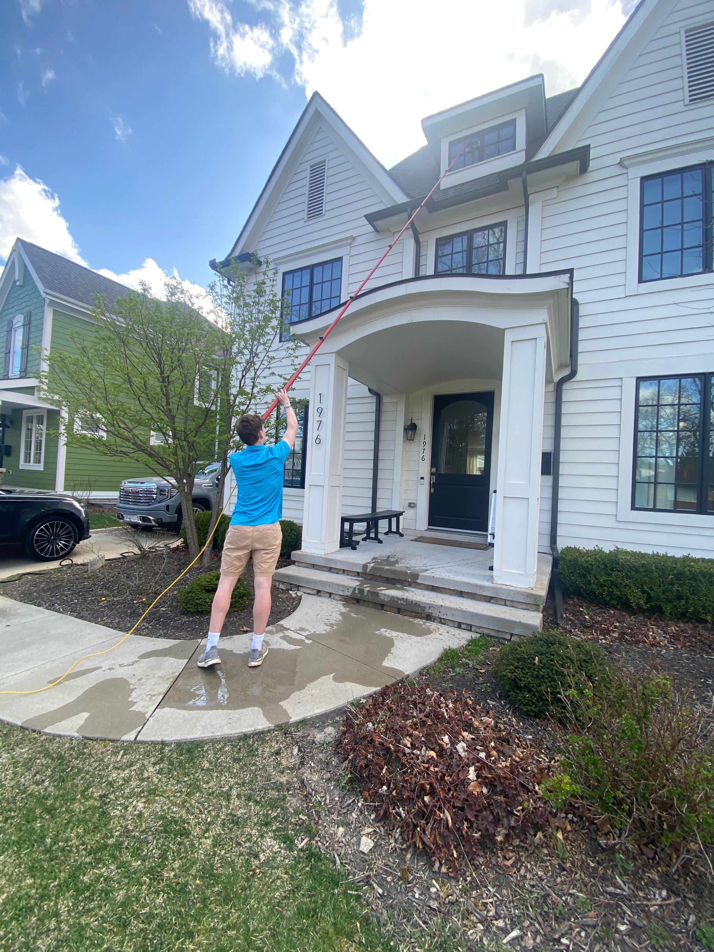 Super Shine Services technician cleaning windows on a stone estate home